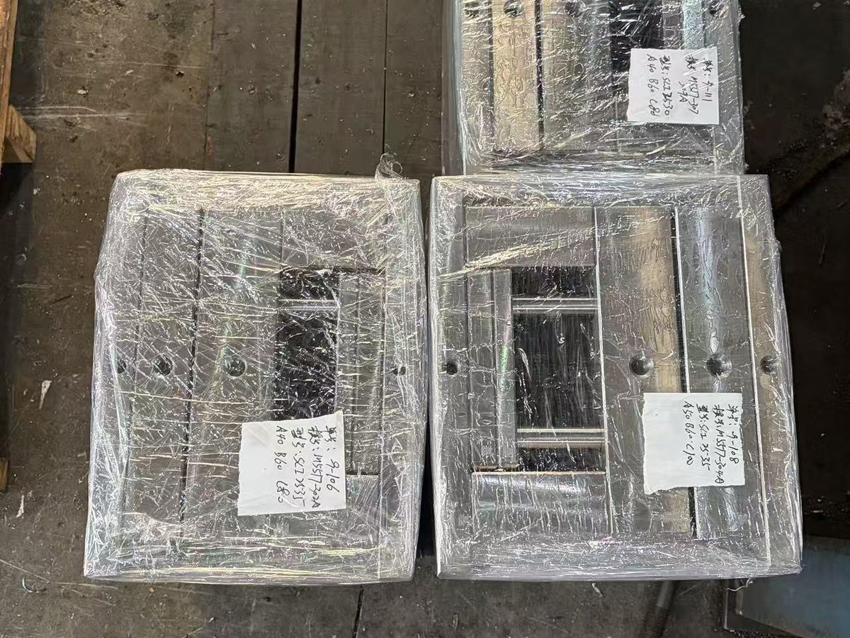 Three standard mold bases wrapped in stretch film and tagged, staged on the workshop floor ready for crating