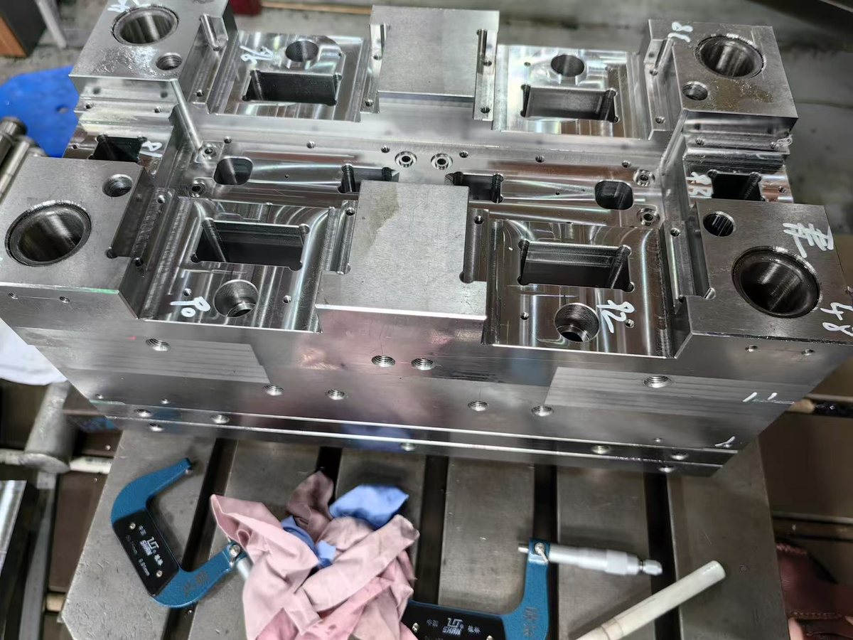 A multi-cavity pocket plate with its corner guide bores, clamped on a machine table at Hsingchao Mould