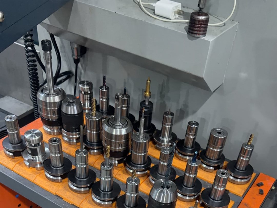 A rack of tool holders and collet chucks on a tool cart beside a machining centre at Hsingchao Mould